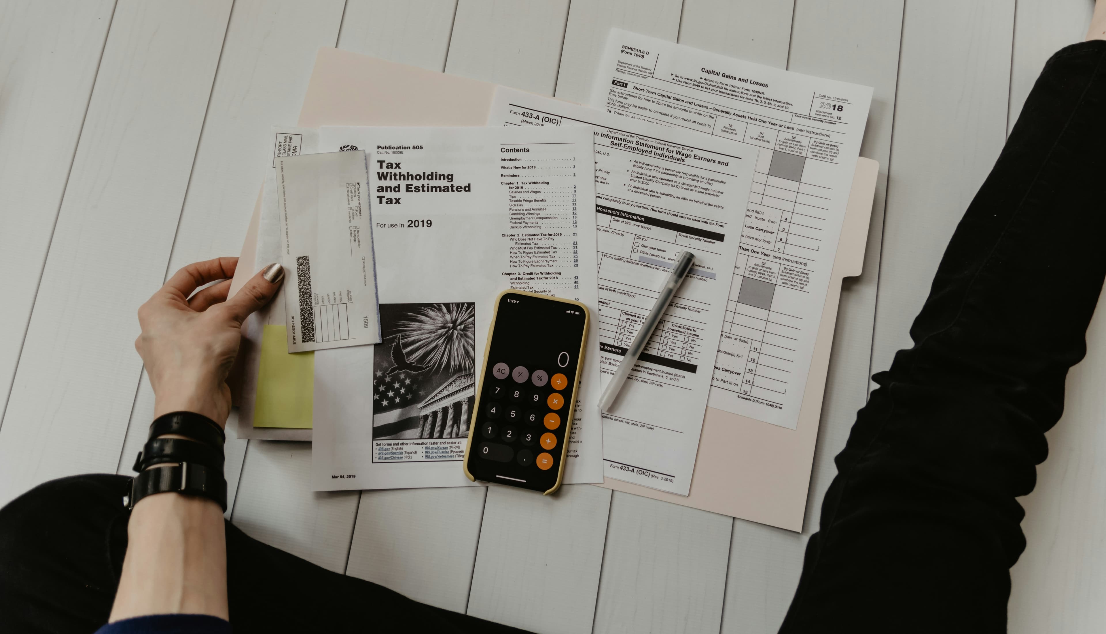 Vacation rental host calculating commission savings with calculator and financial documents